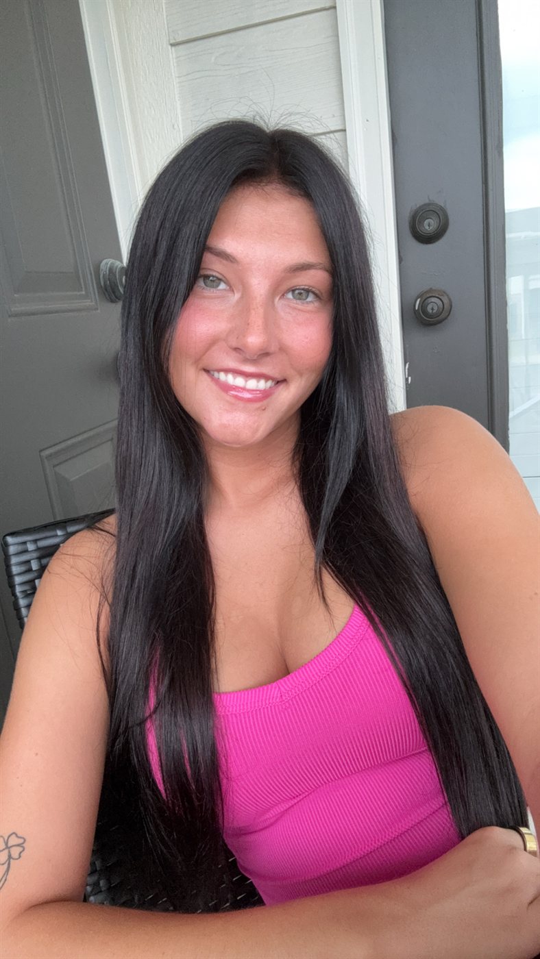 Ella smiling on the porch in a pink top