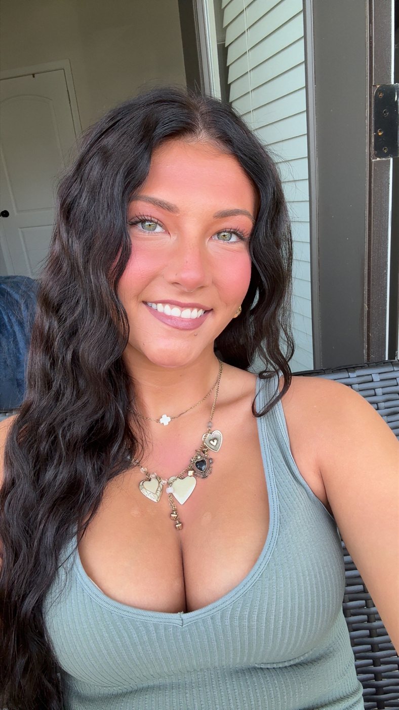 Portrait of Ella smiling in a sage tank top